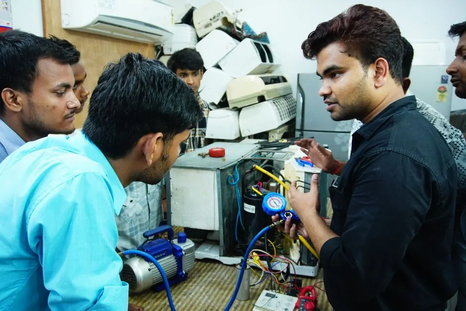 Participants learn AC repair during a hands-on session in Spring Hil, India.